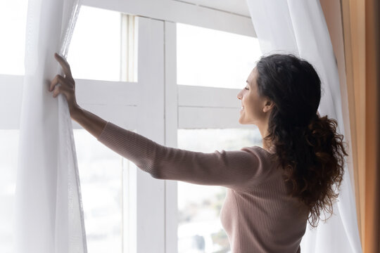 Close Up Smiling Woman Opening Curtains In Morning, Enjoying Sunlight, Standing At Home, Happy Overjoyed Young Female Looking Out Window, Dreaming, Starting New Day, Planning Good Future