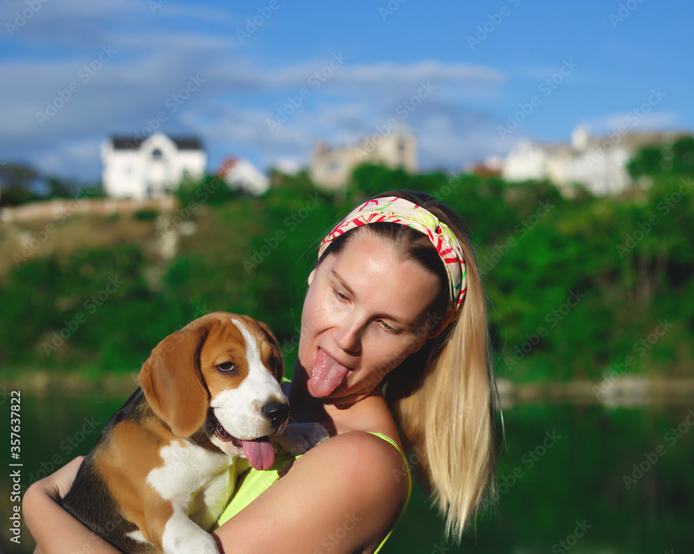 Wall mural portrait of a young woman with a beagle puppy in her arms