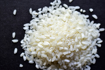 White rice for pilaf spread on a black surface