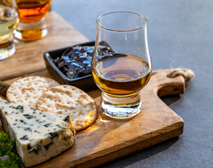 Whiskey and cheese pairing, tasting whisky glasses and plate with sliced cheeses