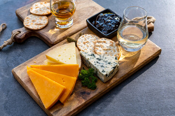Whiskey and cheese pairing, tasting whisky glasses and plate with sliced cheeses