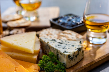 Whiskey and cheese pairing, tasting whisky glasses and plate with sliced cheeses