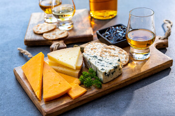 Whiskey and cheese pairing, tasting whisky glasses and plate with sliced cheeses