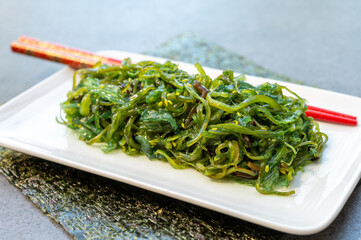 Green fresh oriental seaweed salad served with chopsticks