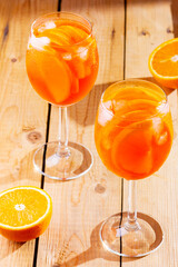 Aperol spritz cocktail on a wooden boards. Two glasses of aperol spritz with orange slised. Summer cocktail in glass. Rustic style