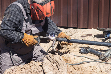 A professional worker welds the pipe using a welding machine. Side view