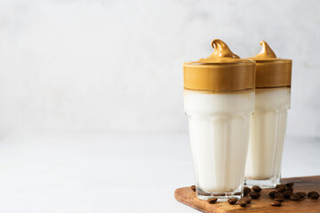 Korean dalgona coffee with brown foam in tall glass close up on white background