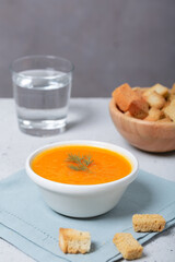 Pumpkin and carrot soup with fresh dill on table