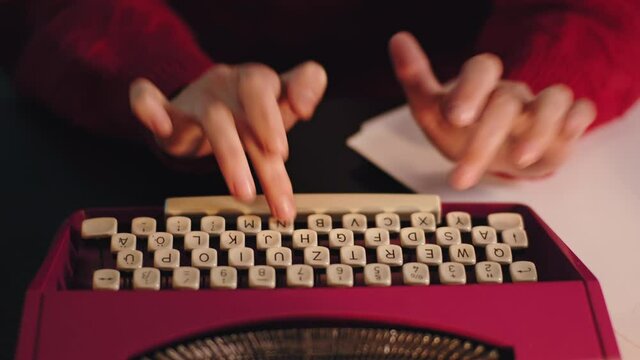 In front of the camera details lady typing some documents on the pink typewriter