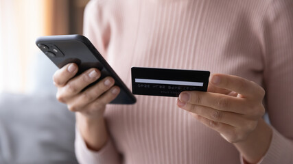 Close up woman paying online by credit card, using smartphone, entering information, young female holding phone, browsing banking service, checking balance, shopping, ordering in internet