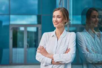 Businesswoman successful woman business person standing arms crossed outdoor corporate building exterior. Smile happy caucasian confidence professional business woman middle age