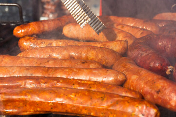 Grilling different kinds of sausages, dry and fresh meat on an open barbeque
