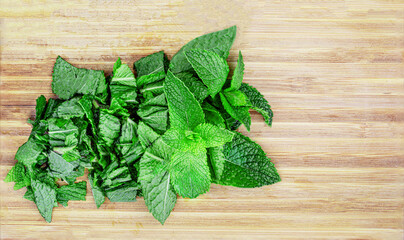 Fresh melissa leaves on wooden cutting board   top view. Chopped mint, copy space. Top view