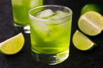 
Green drink with lime and ice on a black background.Close-up.