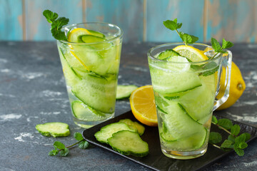 Fresh Cold and refreshing detox water with lemon and cucumber on a stone table.