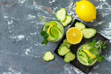 Fresh Cold and refreshing detox water with lemon and cucumber on a stone table. Top view flat lay...