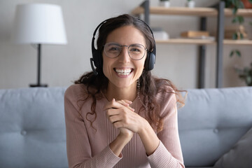 Head shot portrait smiling woman wearing headset with microphone and glasses looking at camera,...