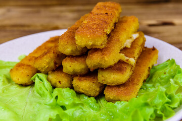 Baked fish sticks and lettuce leaves in a plate