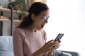 Overjoyed woman with open mouth looking at smartphone screen close up, reading unexpected message, good news, online lottery win, shocked girl wearing glasses received unbelievable shopping offer