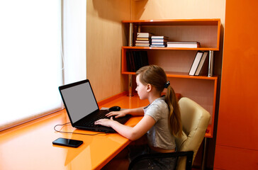 The girl is working on a laptop. Distance learning. Bedroom in the art Nouveau style. Interior of orange furniture.