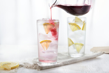 Two glasses of ice cold lemonade. Pour the syrup from the jug into the glass.