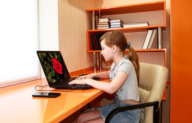 The girl is working on a laptop. Distance learning. Bedroom in the art Nouveau style. Interior of orange furniture.