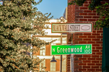 Fototapeta na wymiar Black Wall Street and N Greenwood Avenue street signs - closeup - in Tulsa Oklahoma with bokeh background