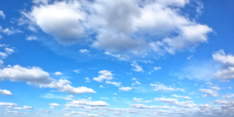 Naklejka na ściany i meble White clouds on a blue sky as a background. Sunny weather.