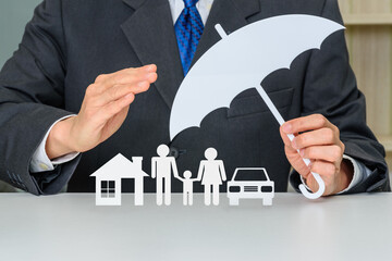 Broker / insurer holds an umbrella to protect parents e.g. father, mother, a child, a house and a...