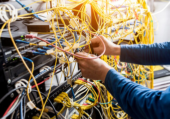 Network engineer working in server room. Connecting network cables to switches