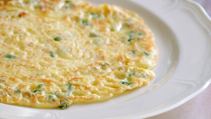 Egg omelette with spring onion, served on a plate.