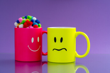 Two mugs with  happy and sad emotions on the background. Concept, Coffee Mugs with sadness and...