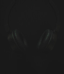 Fototapeta na wymiar Black earphones on a black background for inscription