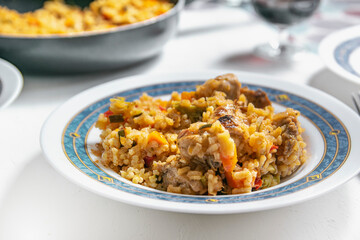 Typical Spanish rice with rabbit and vegetables recipe served on a white plate. Empty copy space for Editor's content.