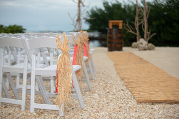 Folding white chairs with pink lsashes and brown starfish hanging from chairsl at beach wedding...