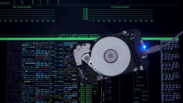 Work of hacked hard drive inside. Hacker breaks sensitive data from a hard drive. Against the background, lines of code and data flash. Cybersecurity. Government secret data hacking technology