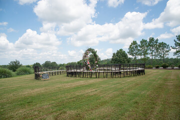 Unique round spiral chair pattern wedding ceremony setting at rolling hills countryside with brown chiavari chairs and white cushions