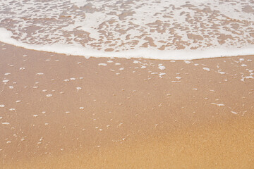 Fototapeta na wymiar White foam on a sandy beach. Copy space.