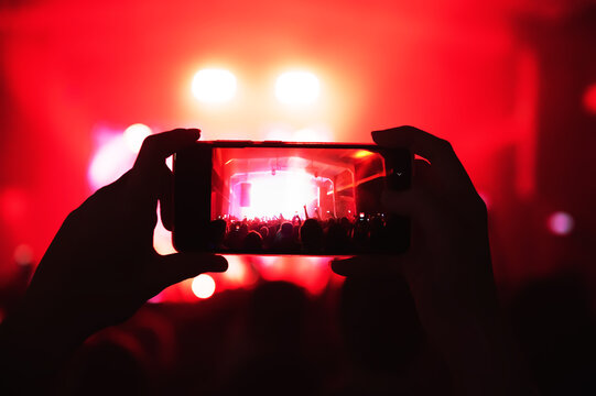 Man At A Concert Shoots Videos And Photos Of The Crowd And Stage On A Smartphone. Music Festival. Red Light Show