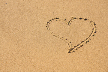 A heart symbol written on sand as a background. Valentines day concept.