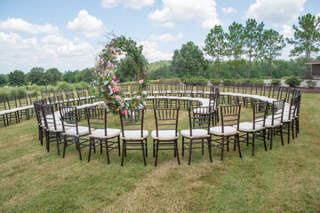 Unique round spiral chair pattern wedding ceremony setting at rolling hills countryside with brown chiavari chairs and white cushions