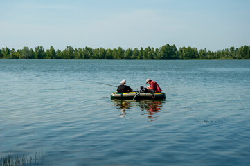 Men on an inflatable boat in the river fishing with fishing rods