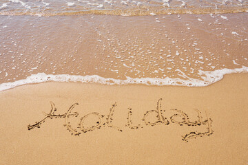 Holiday inscription on a tropical sandy beach with waves and foam on a background.