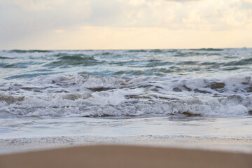 Fototapeta premium Blurred sea wave with foam on a sandy beach with horizont as a natural background/texture.