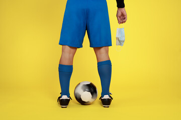 football player with face mask in hand and ball between legs