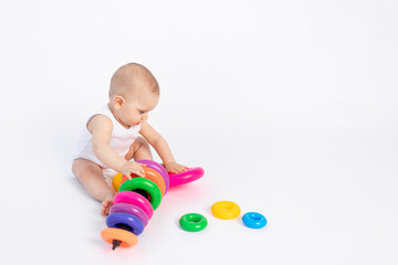 Obraz premium cute baby boy 8 months old playing with a pyramid on a white isolated background, place for text, early development of children
