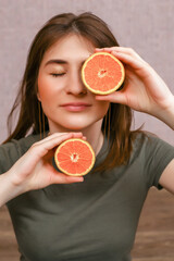 girl with closed eyes and fruit on a light background. in the hands of a beautiful young woman of half cut oranges on a uniform distance from each other near the face