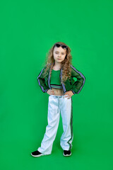 beautiful fashionable 6-year-old girl on a green isolated background with curly hair and glasses