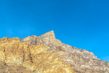 Peak of a steep and rocky mountain in Provo Canyon Utah against clear blue sky