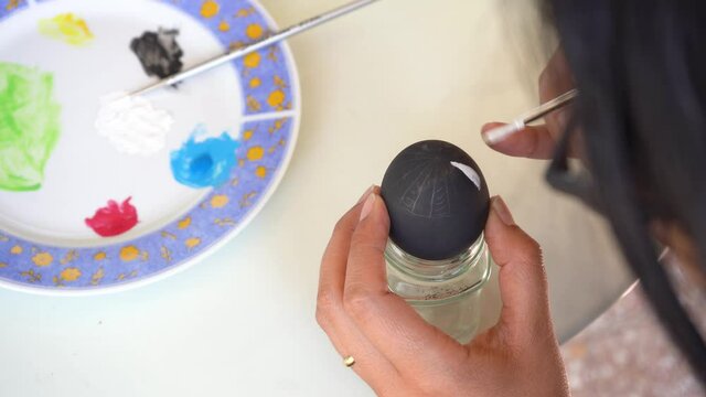 Close up of a caucasian woman starting to paint details on a ester egg